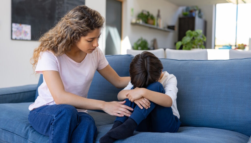 mom comforting sad child on a couch_credit iStock-1421125373 (1)