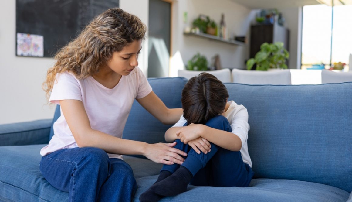 mom comforting sad child on a couch_credit iStock-1421125373 (1)