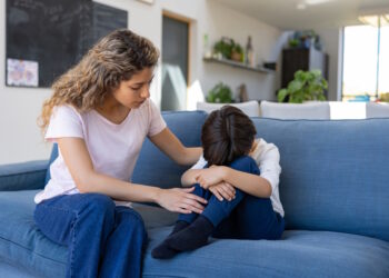 mom comforting sad child on a couch_credit iStock-1421125373 (1)