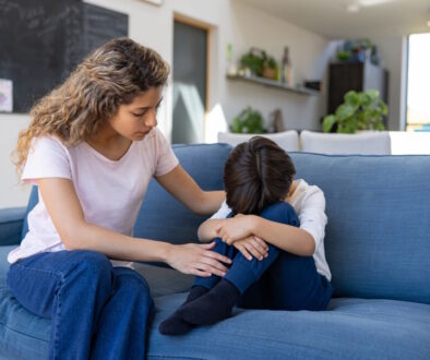 mom comforting sad child on a couch_credit iStock-1421125373 (1)